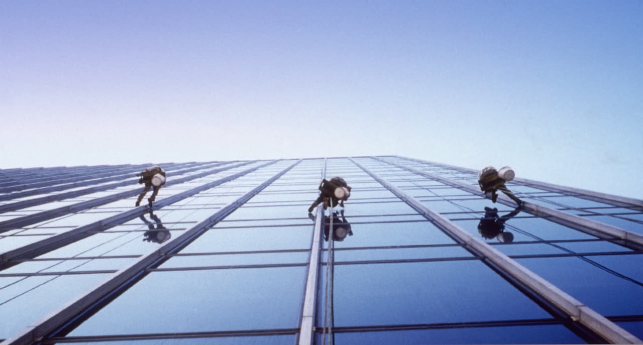 Window cleaners on harnesses cleaning the side of a building