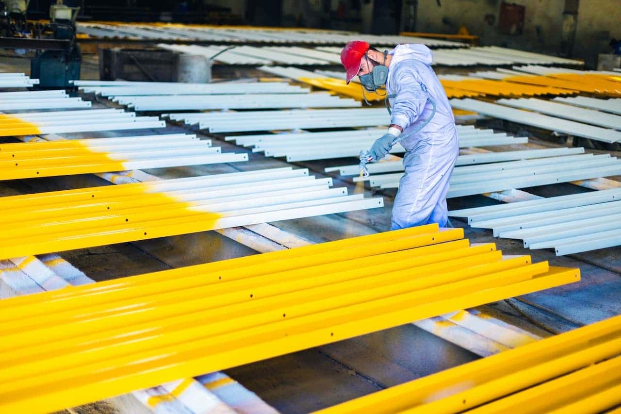 Person spray painting metal sheets in warehouse