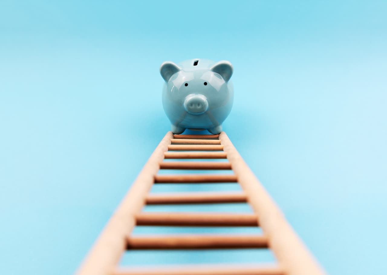 Blue piggy bank climbing a ladder