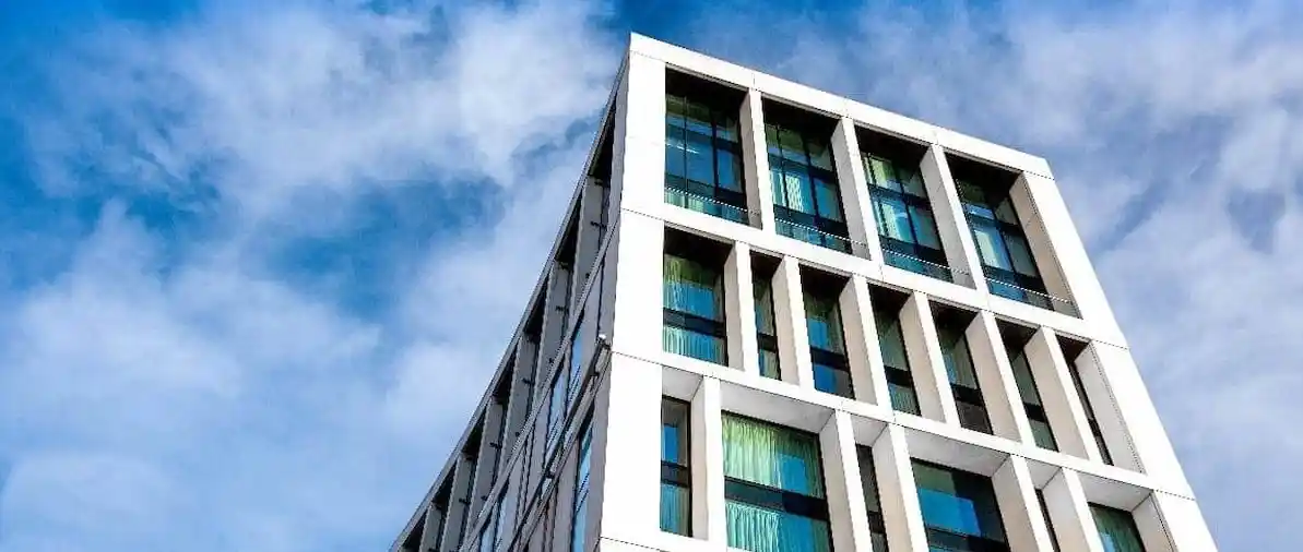 A high-rise building with windows, contrasted by a sunny sky backdrop.