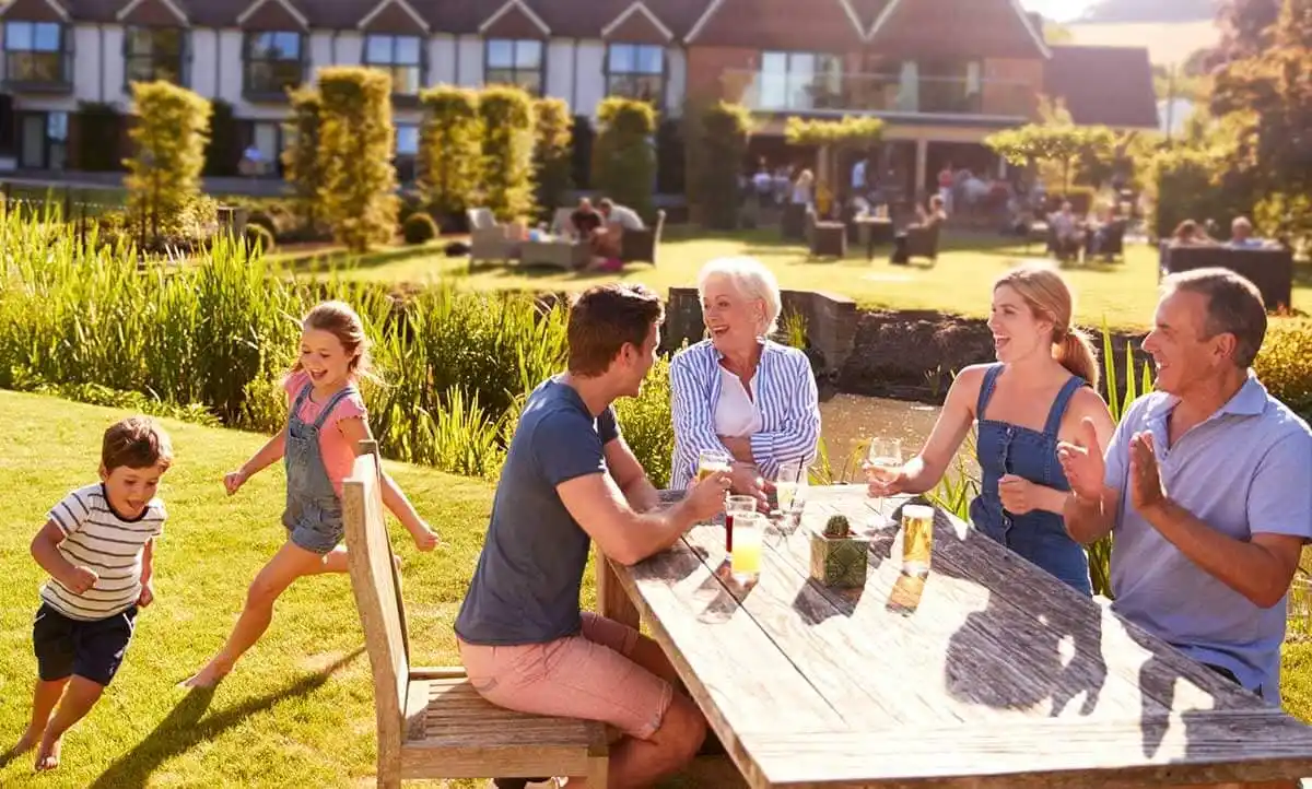 A family gathered around a table in a garden restaurant, enjoying a meal together and sharing smiles