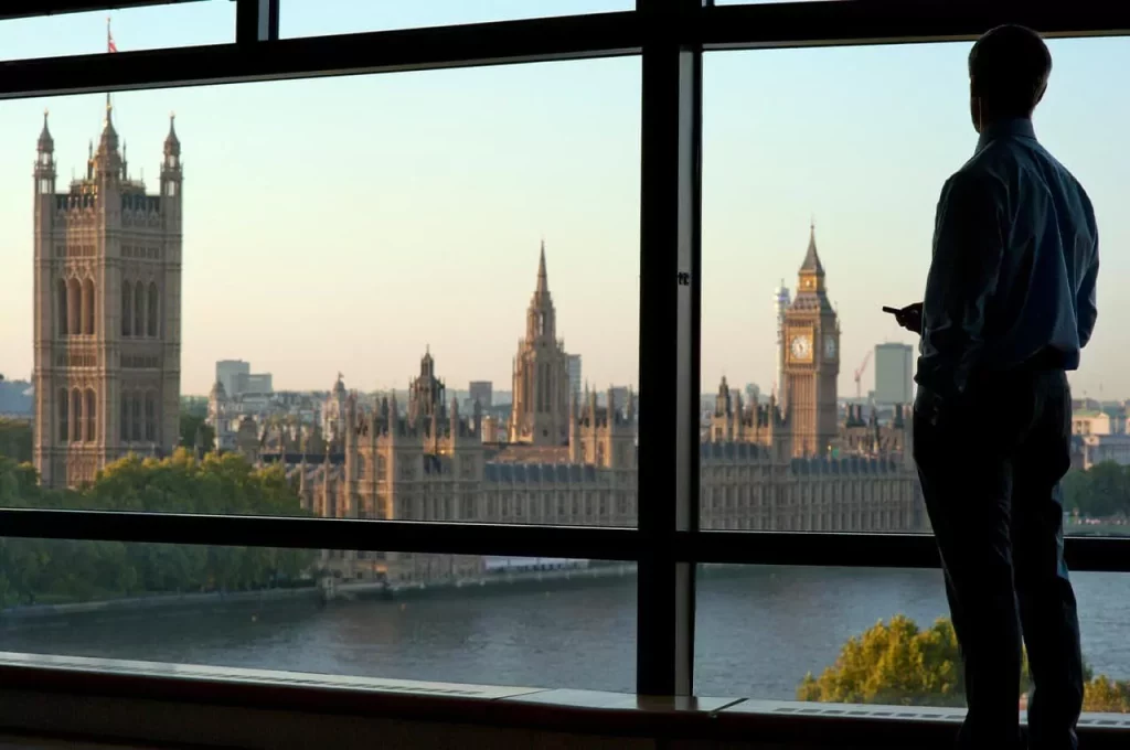 Person looking out of a window at Westminster and the London skyline