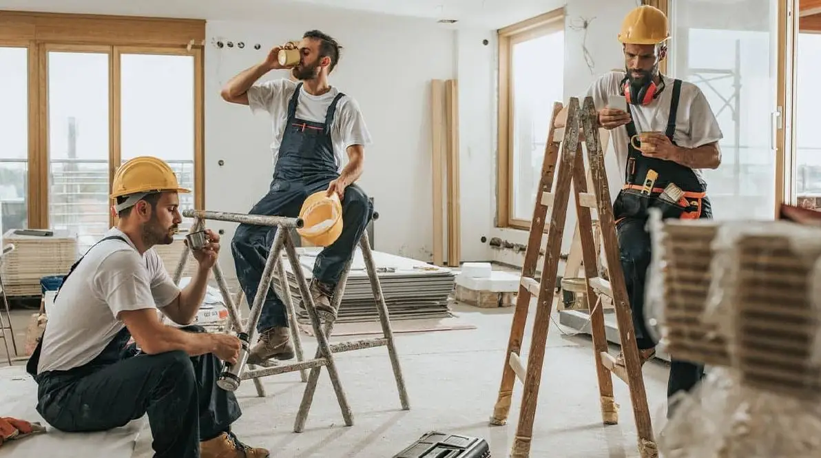 Three men wearing hard hats are working together on a construction site