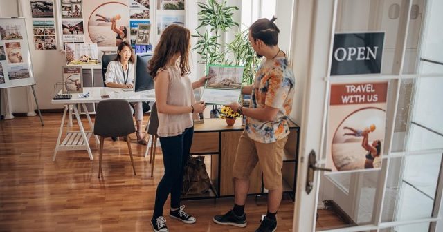 Two customers looking at a brochure in a travel office with a travel agent.