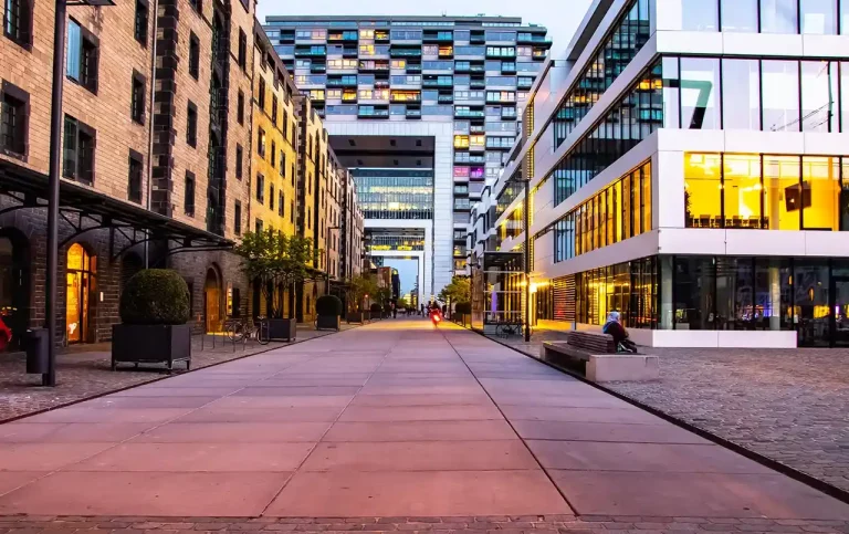 Urban street with modern buildings on both sides. A tall residential building is in the background.