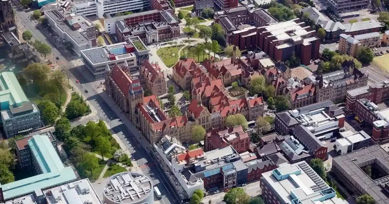 Aerial view of a university campus with red brick buildings and next to a big road.