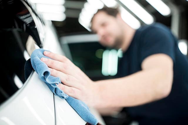 A car valet cleans car with a cloth.