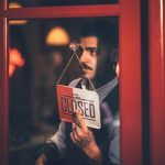 Barber is closing down his shop and hangs a 'Closed' sign at the door.