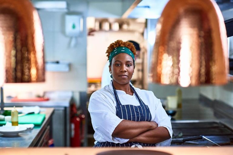 Female chef standing confidently in a professional kitchen.