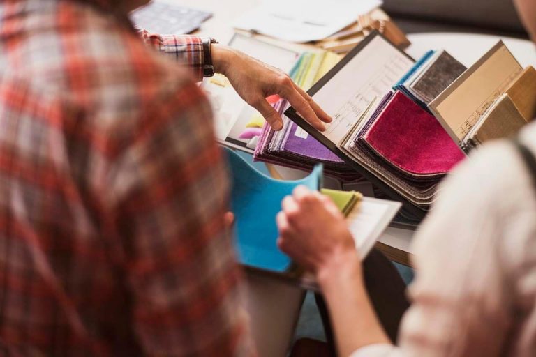 Two people selecting samples from a selection of vibrant fabrics at a furniture shop.
