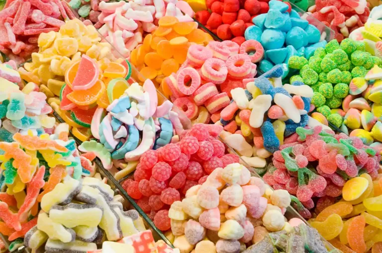 Brightly colored gummy candies displayed in a sweet shop, including rings, berries, and cherries.