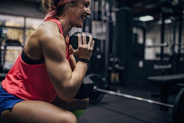 Person performing a squat with dumbbell in the gym, focused on the exercise.