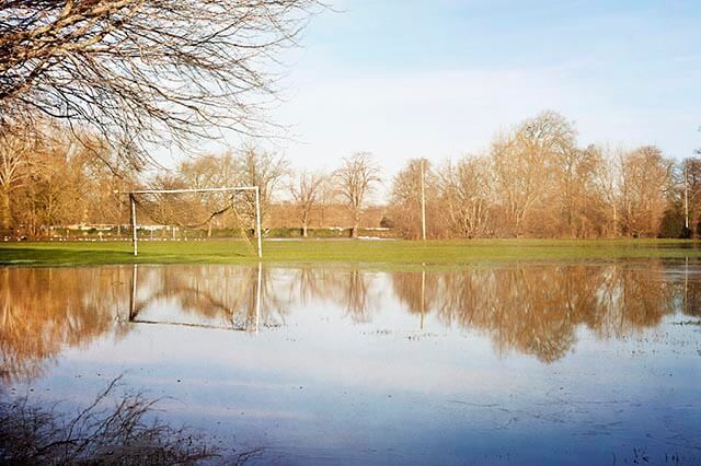 A flooded football pitch with standing water covering the grass.