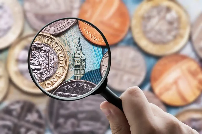 A magnifying glass focusing Great Britain Pound (GBP) currency coins and notes. Test.