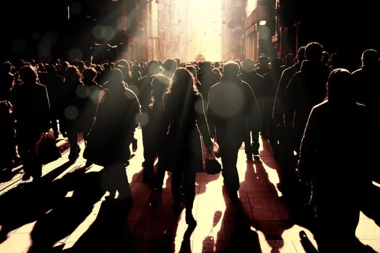 Lots of people casting shadows down a highstreet