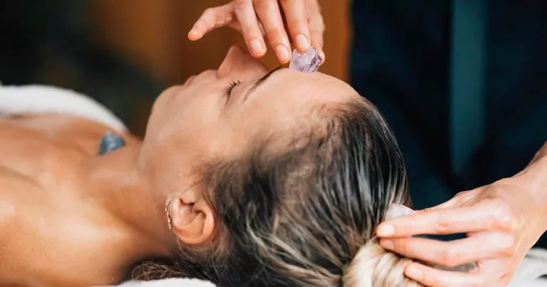 Person receiving crystal therapy with crystals placed on the top of their head and forehead.