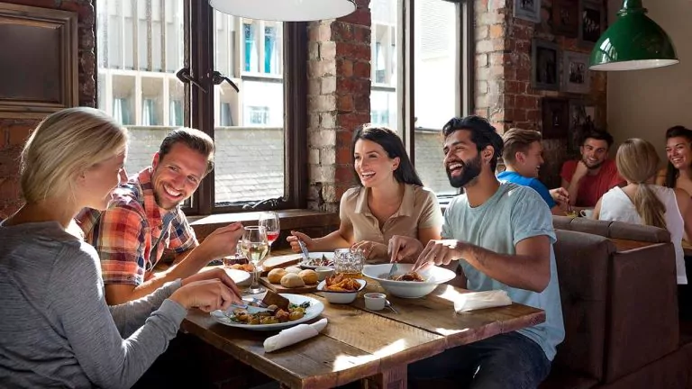 Restaurant customers enjoying a meal together at a table, smiling and talking in a warm, inviting atmosphere.