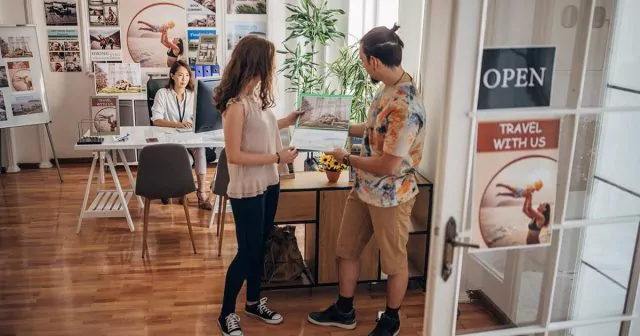Two customers looking at a brochure in a travel office with a travel agent.