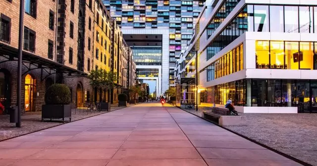 A paved urban walkway surrounded by residential buildings with brick facades, large windows, and balconies.