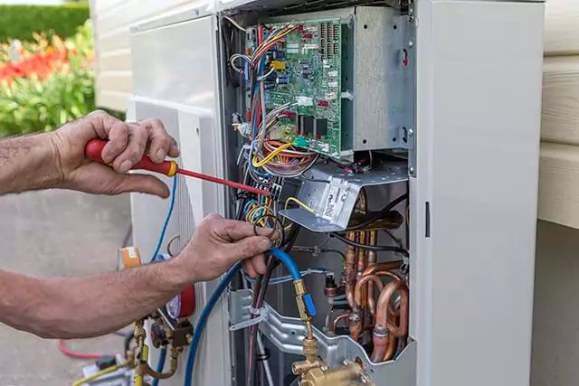 A contractor working on an electrical heating system with colourful wires and a circuit board.