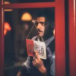 Barber is closing down his shop and hangs a 'Closed' sign at the door.