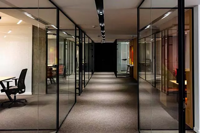 Modern office with a spacious hallway and glass walls creating multiple visible meeting areas.