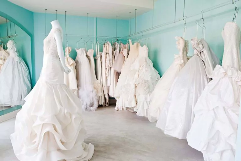 Bridal shop display with white wedding dresses on hangers and a mannequin in a gown.