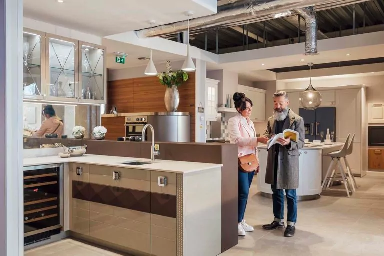 Man and woman admiring kitchen cabinets and countertop in a modern showroom.