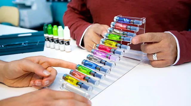 Two people examining colorful vape cartridges in a vape store.